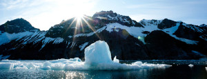 Backlit iceberg floats in a fjord in northern arctic showing a lack of ice floes due to climate crisis